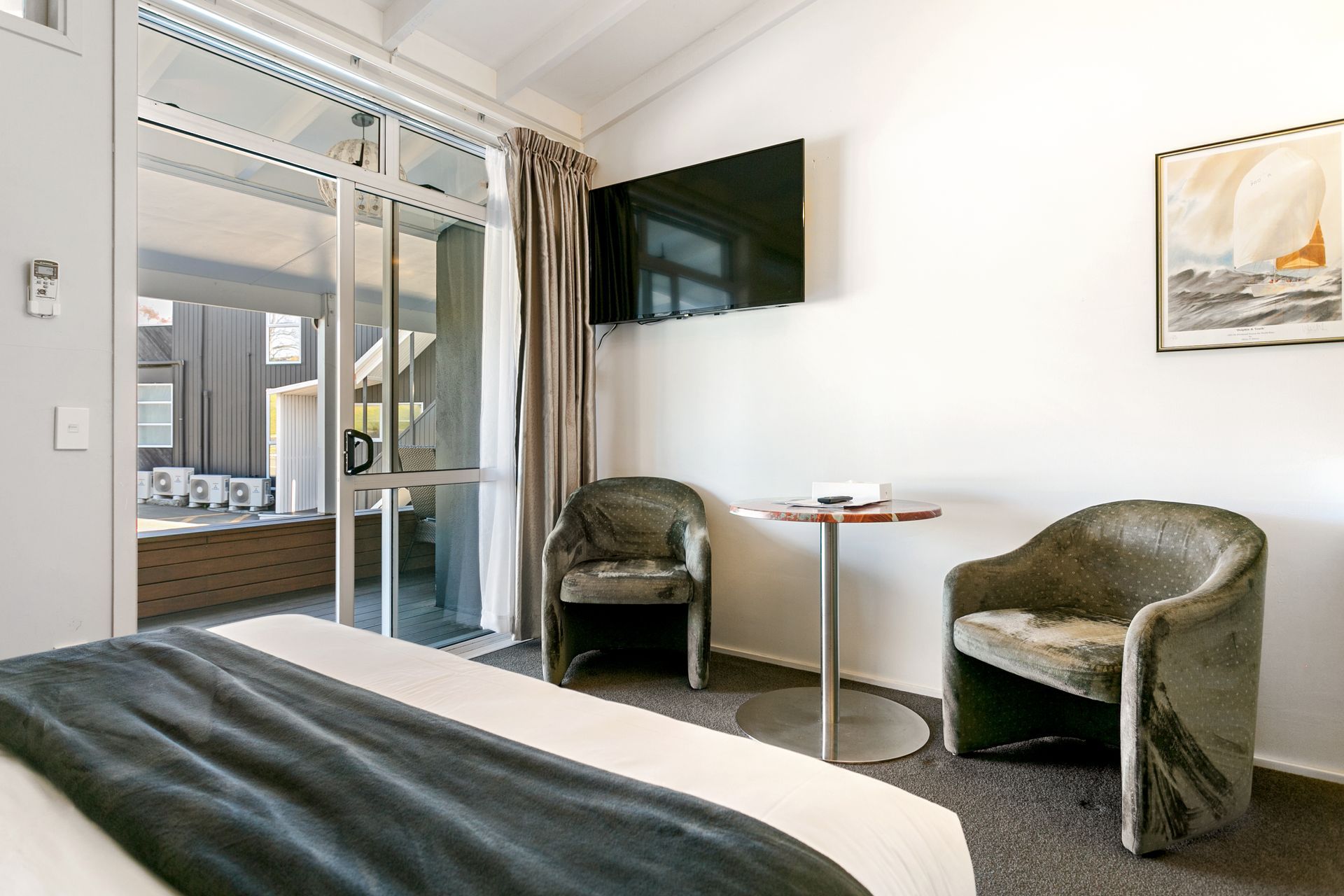 A hotel room with a bed , chairs , table and television.