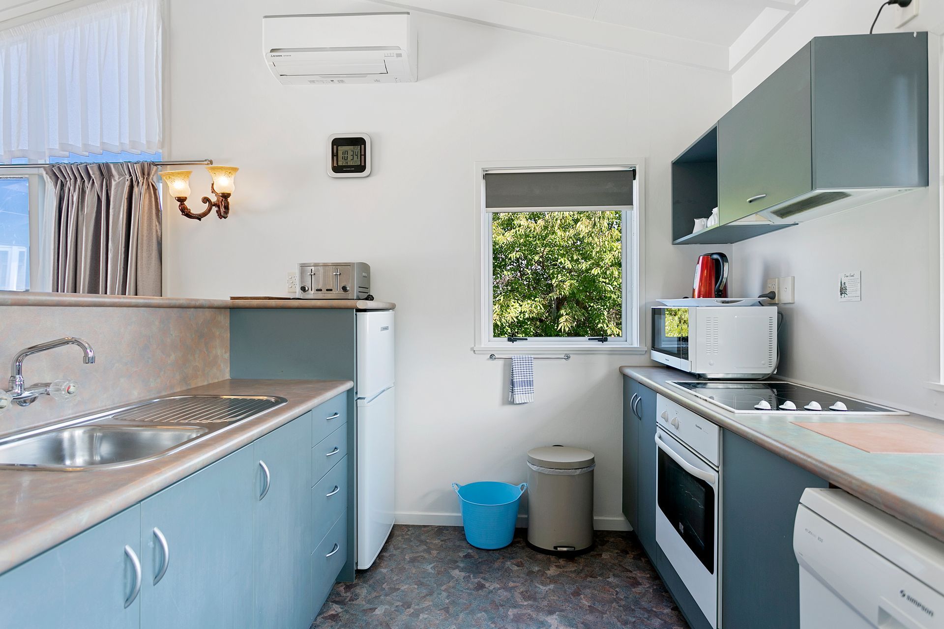 A kitchen with blue cabinets and white appliances and a window.