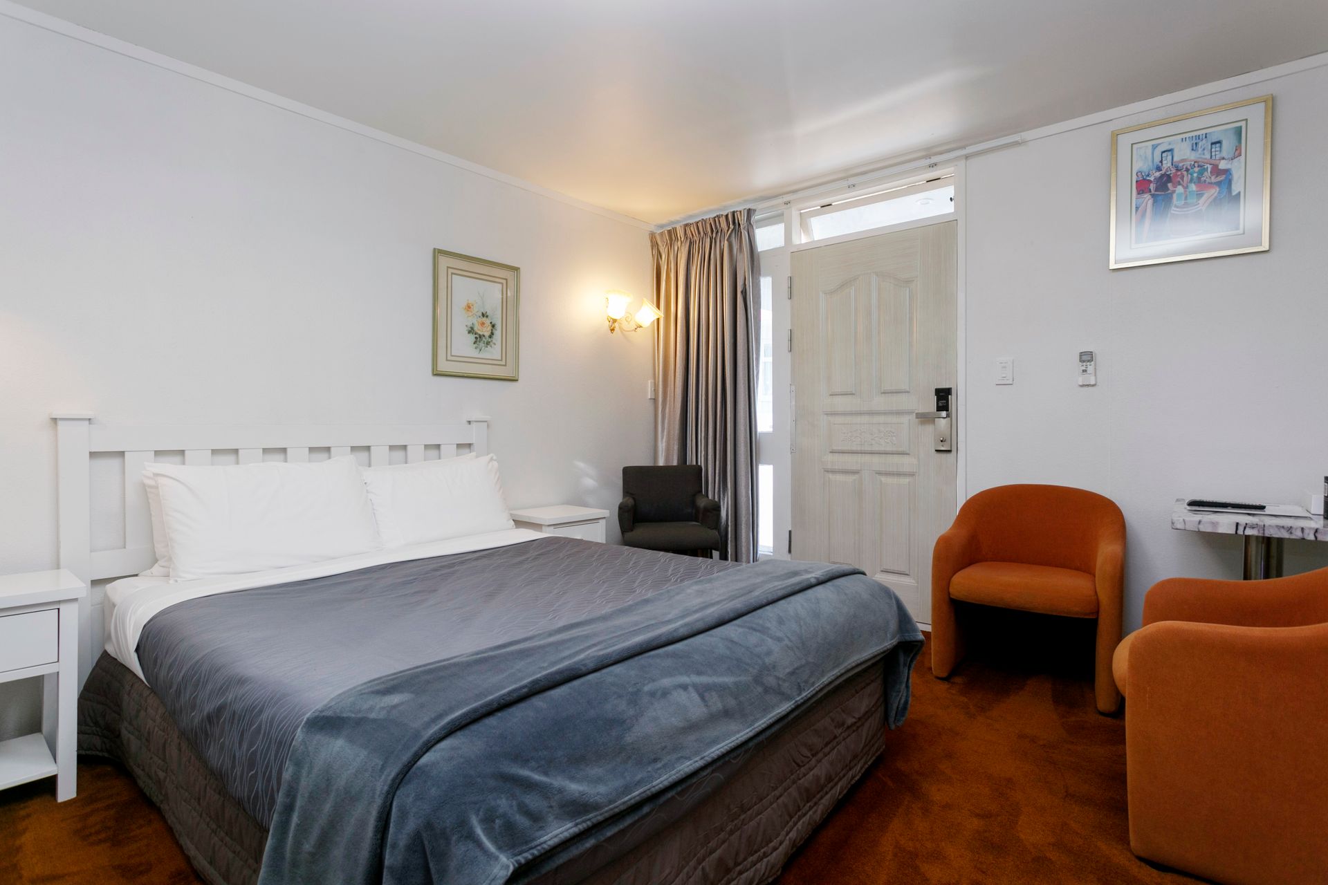 A hotel room with a king size bed and two chairs.