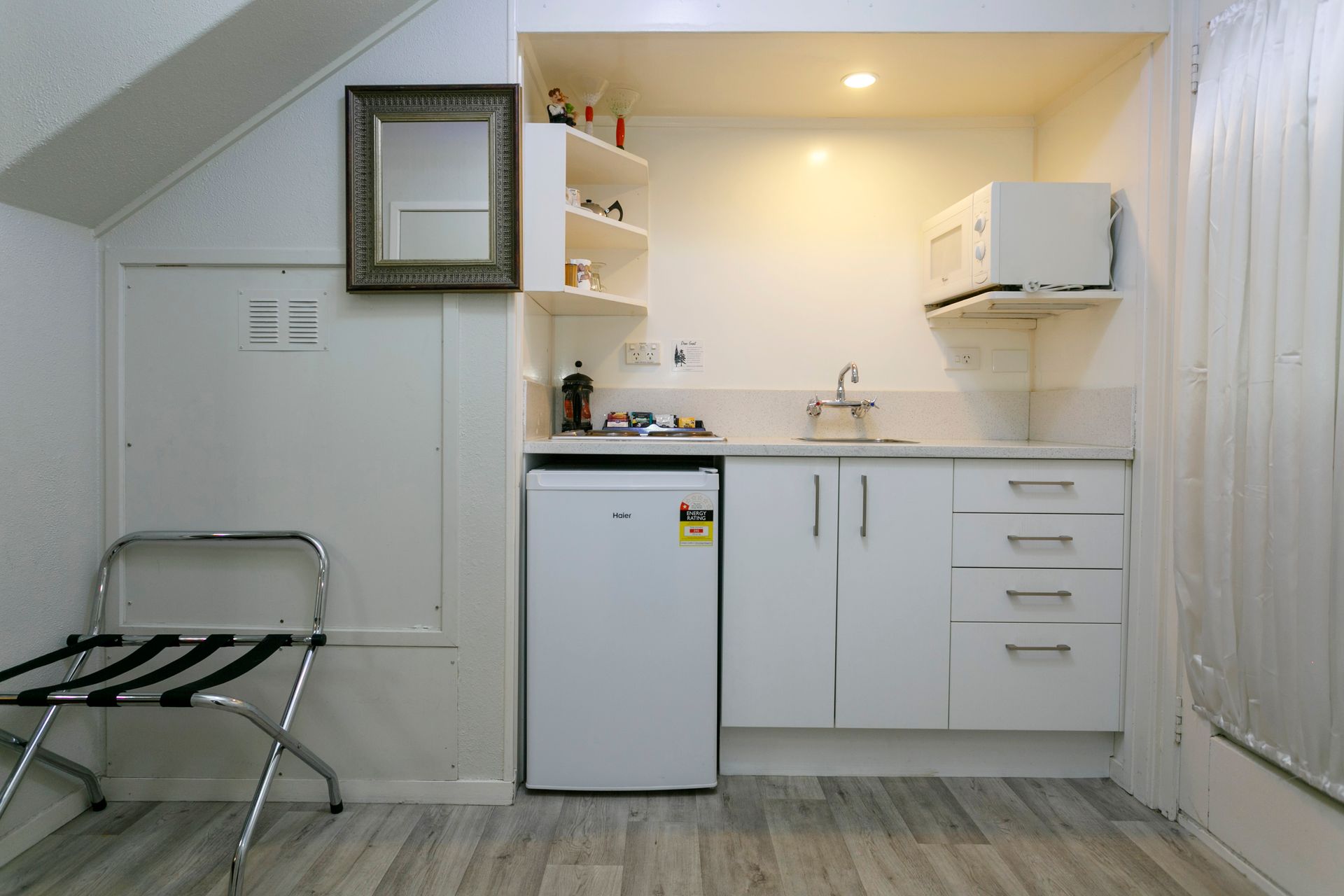 A small kitchen with white cabinets , a refrigerator , a microwave and a sink.