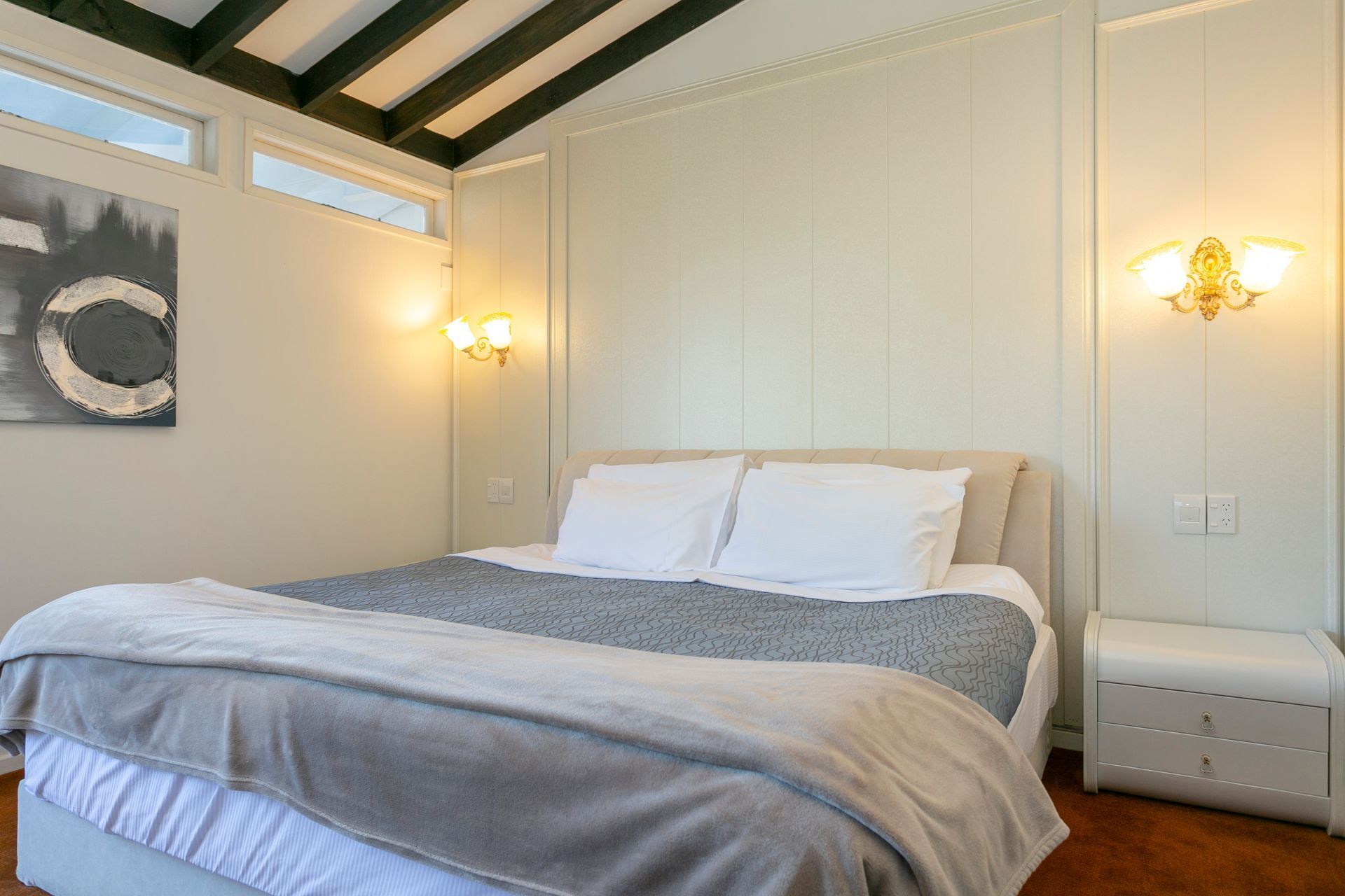 A bedroom with a king size bed and a painting on the wall.