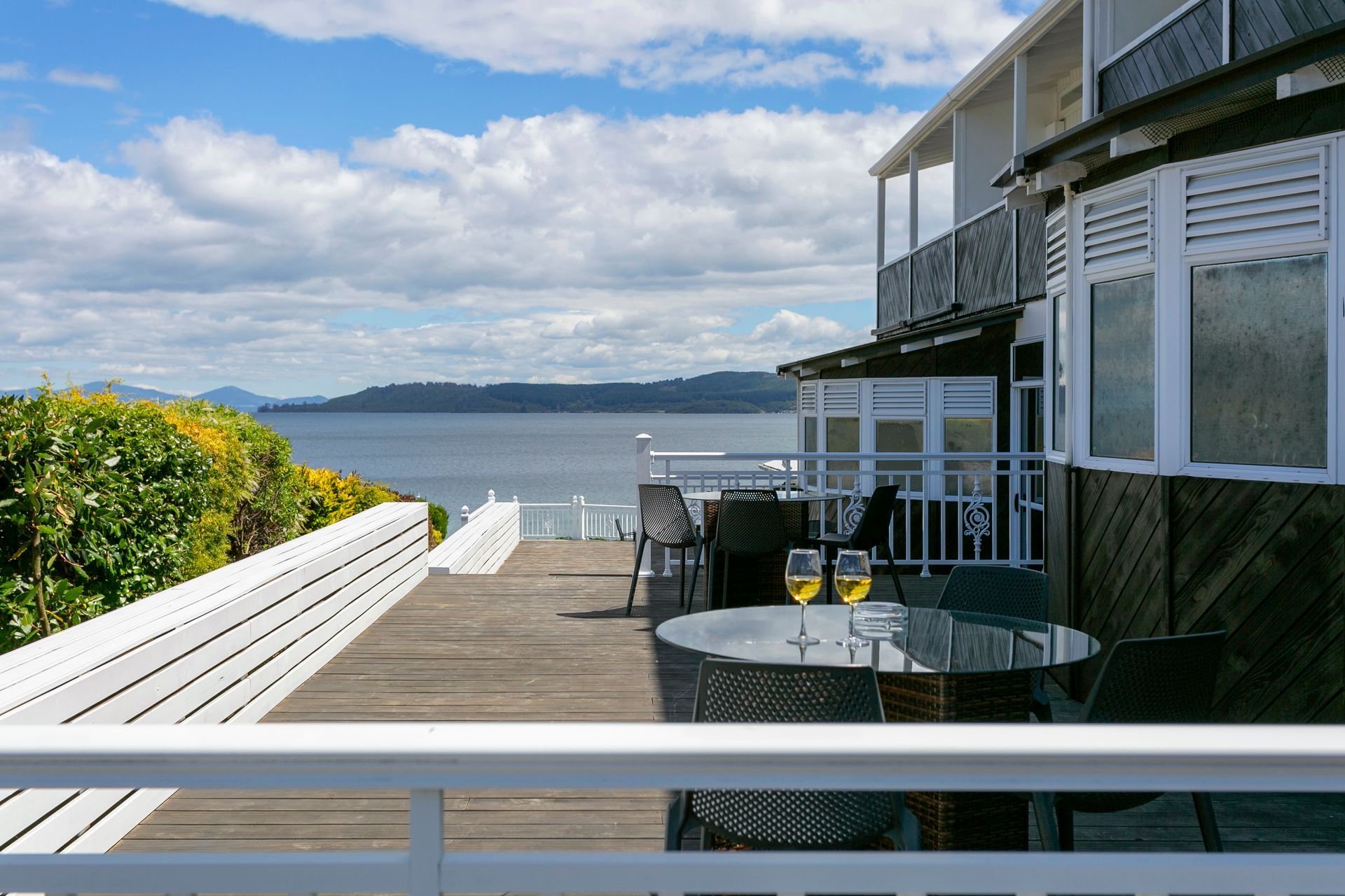 A balcony with a table and chairs overlooking the ocean.