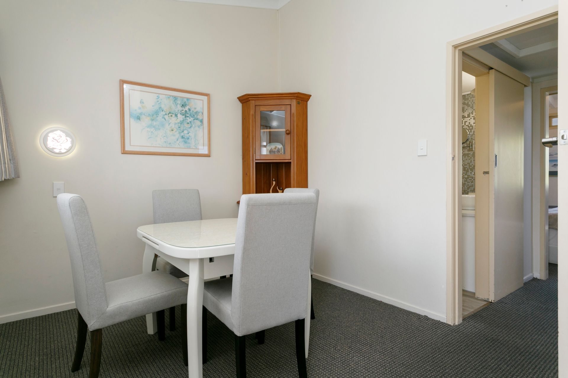 A dining room with a table and chairs and a picture on the wall.