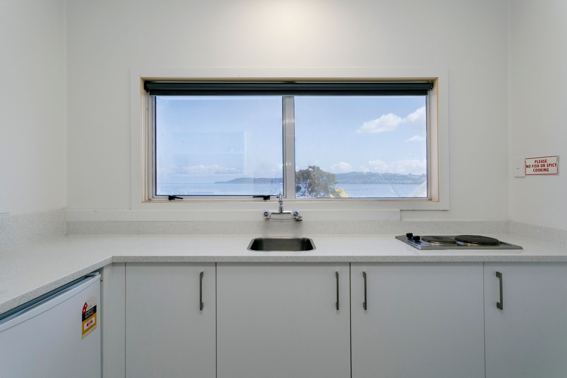 A kitchen with a sink and a window overlooking the ocean.