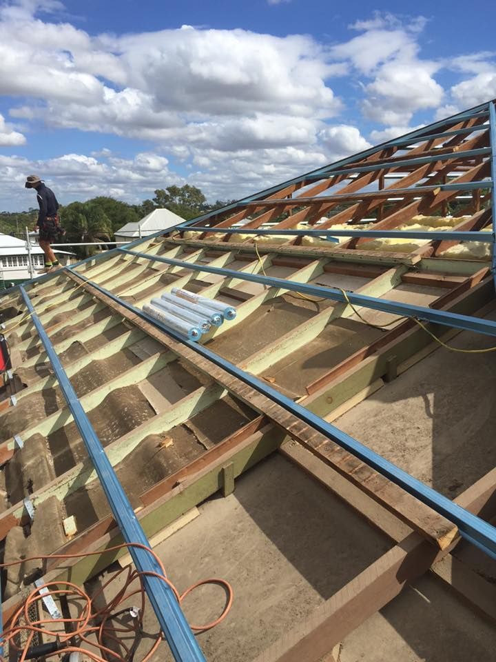 A Man is Standing on Top of a Wooden Roof — Bradshaw Plumbing & Roofing Pty Ltd In East Mackay, QLD