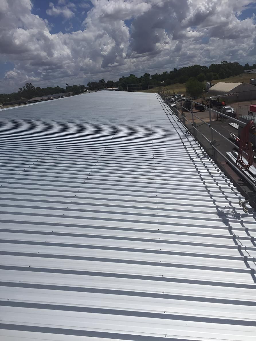 A Large Metal Roof With a Blue Sky in the Background — Bradshaw Plumbing & Roofing Pty Ltd In Rural View, QLD