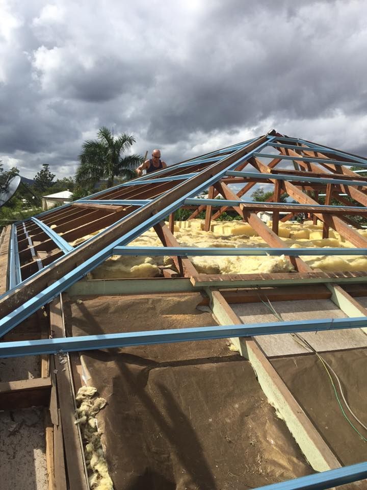 A Man is Working on the Roof of a House — Bradshaw Plumbing & Roofing Pty Ltd In Rural View, QLD