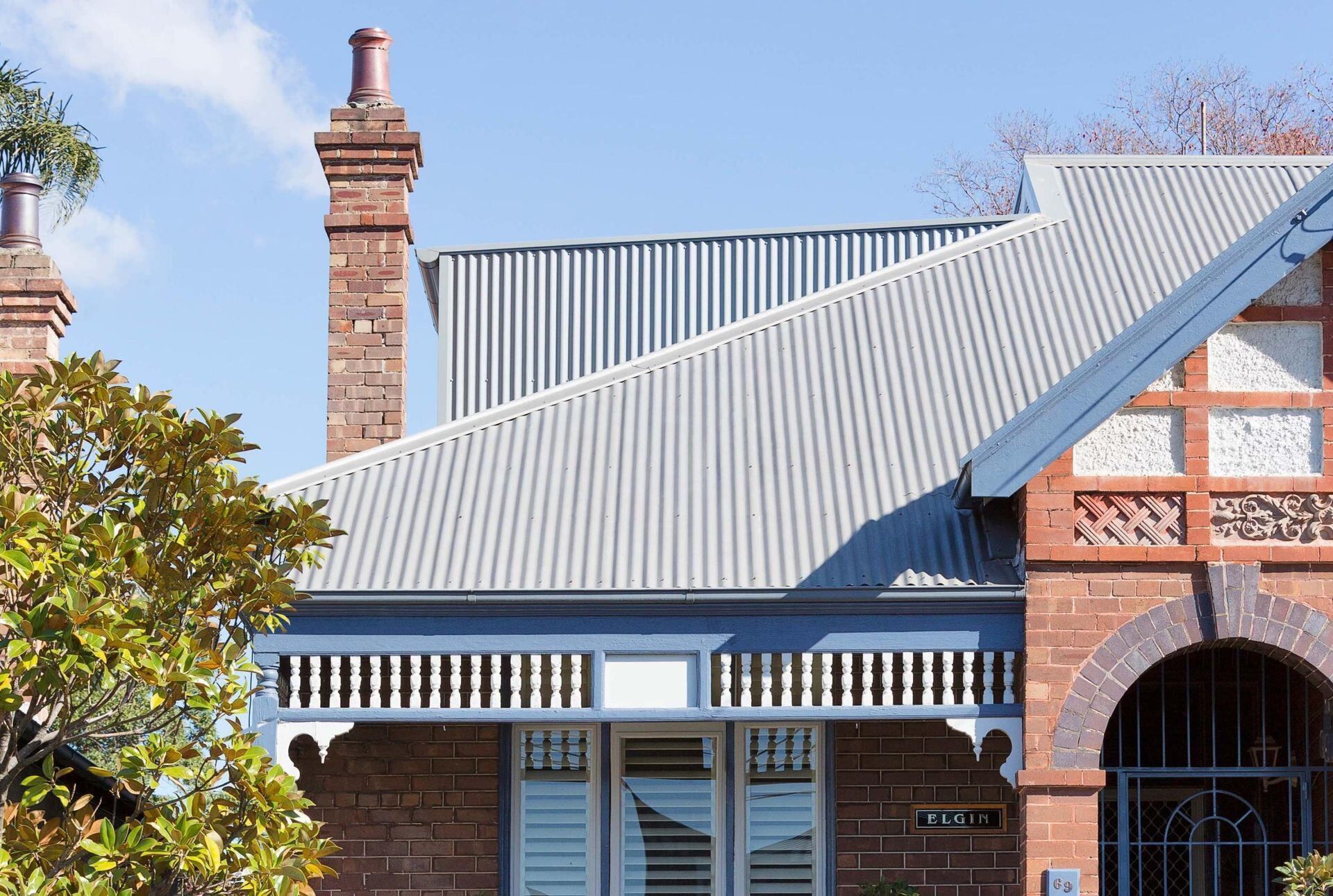 A Brick House With a Metal Roof and Chimneys — Bradshaw Plumbing & Roofing Pty Ltd In Paget, QLD