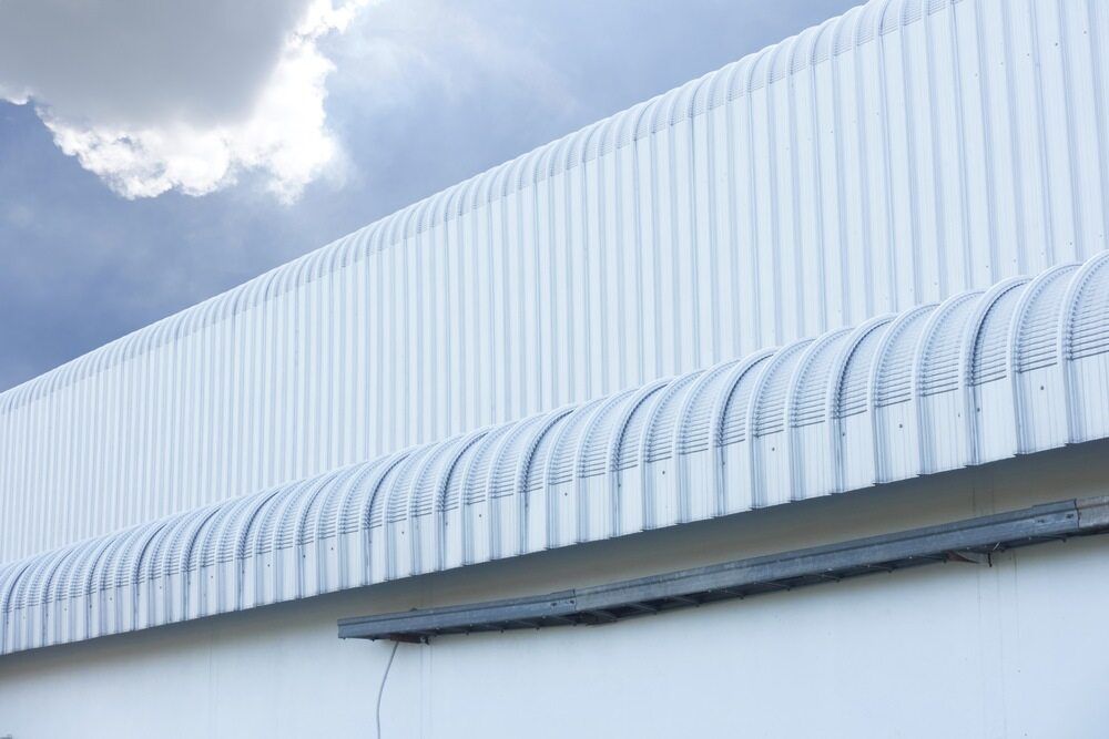 A White Building With a Curved Roof and a Blue Sky in the Background — Bradshaw Plumbing & Roofing Pty Ltd In Paget, QLD