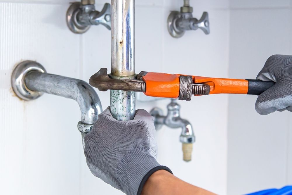A Plumber is Fixing a Sink Pipe With a Wrench — Bradshaw Plumbing & Roofing Pty Ltd In Paget, QLD