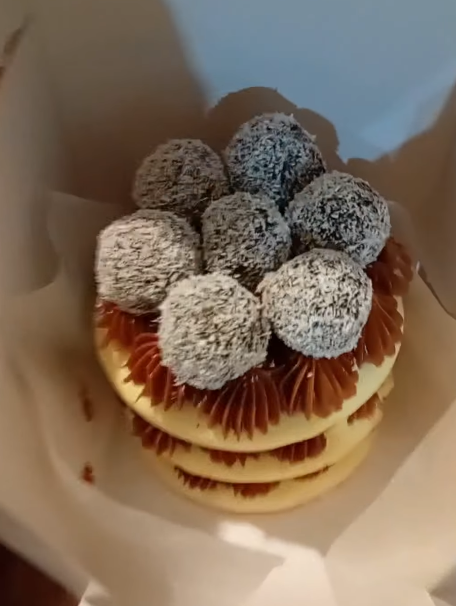 Pila de panqueques con nata montada y fresas cubiertas de chocolate en un recipiente para llevar