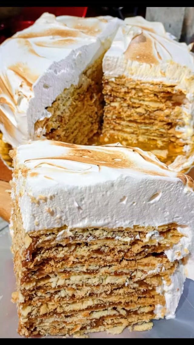 Postre en capas apiladas con glaseado blanco y un hilo de caramelo, cortado para mostrar muchas capas finas y doradas