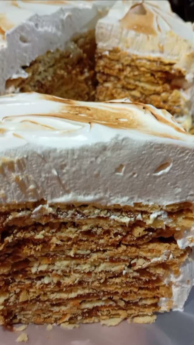 Primer plano de un postre en capas con cobertura blanca y la parte superior bañada en caramelo