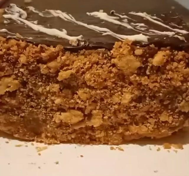 Primer plano de una porción de pastel de chocolate con migas, cubierta de glaseado y una capa crujiente de color marrón.