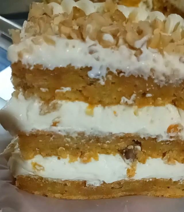 Pastel de capas relleno de crema, cubierto con frutos secos picados y migas doradas