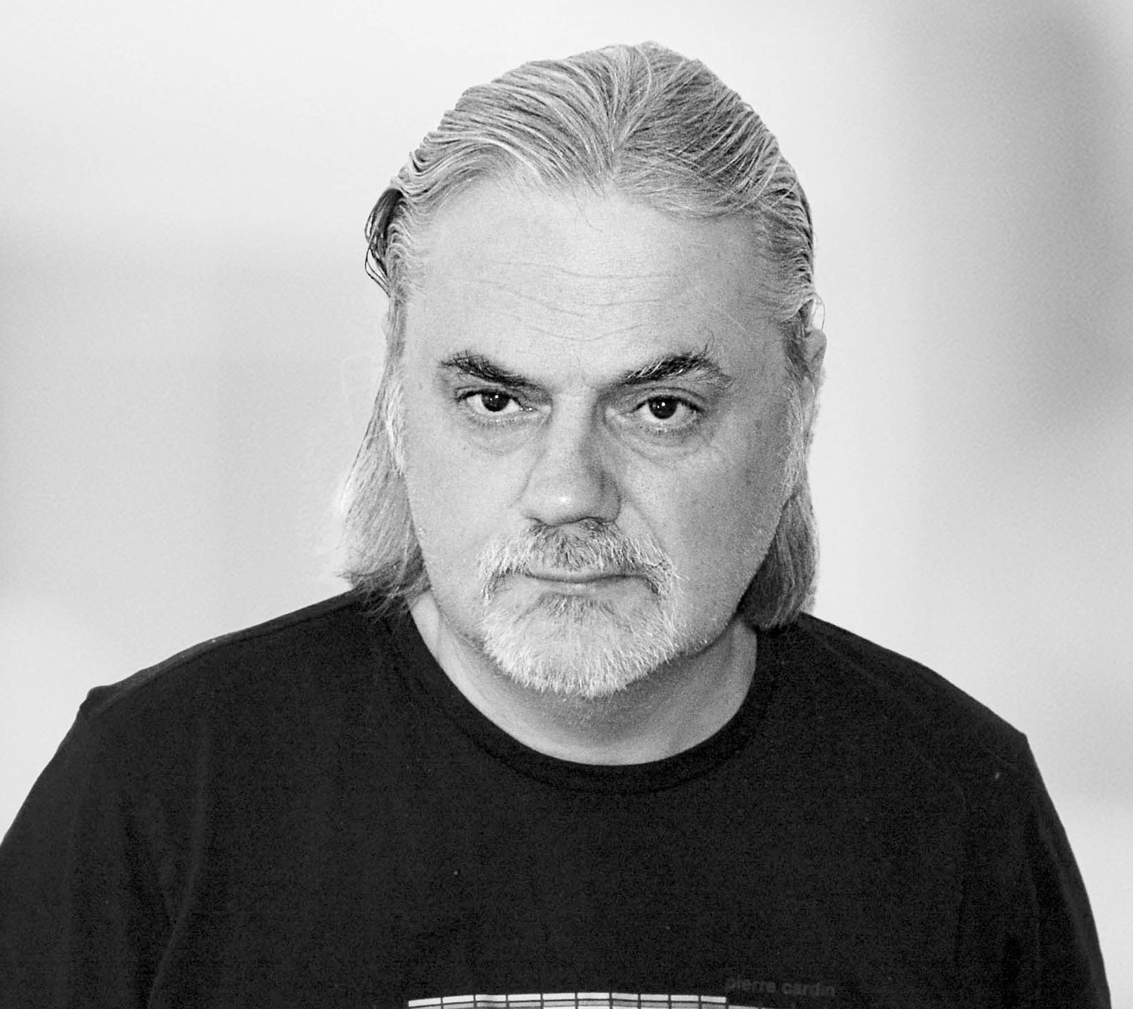 Auf einem Schwarzweißfoto ist ein Mann  in einem schwarzen T-shirt.