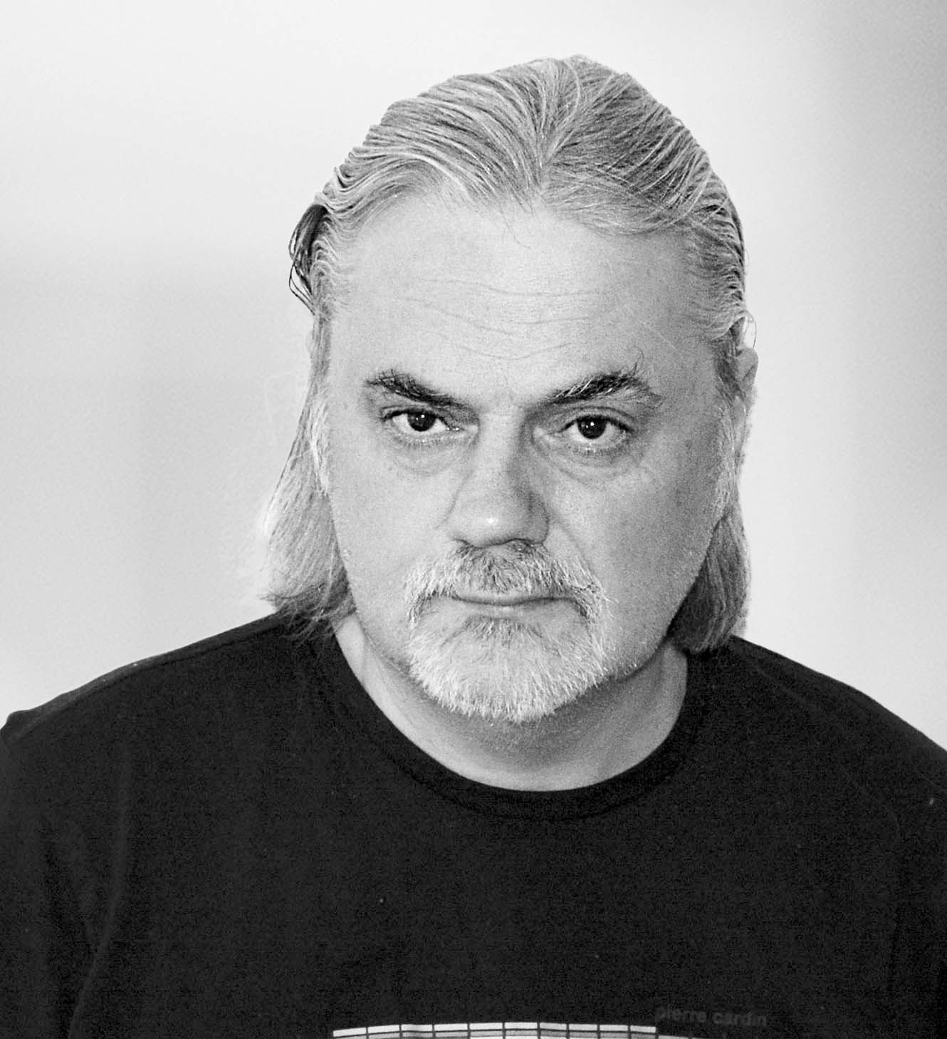 Ein Mann mit Brille und Bard lächelt.