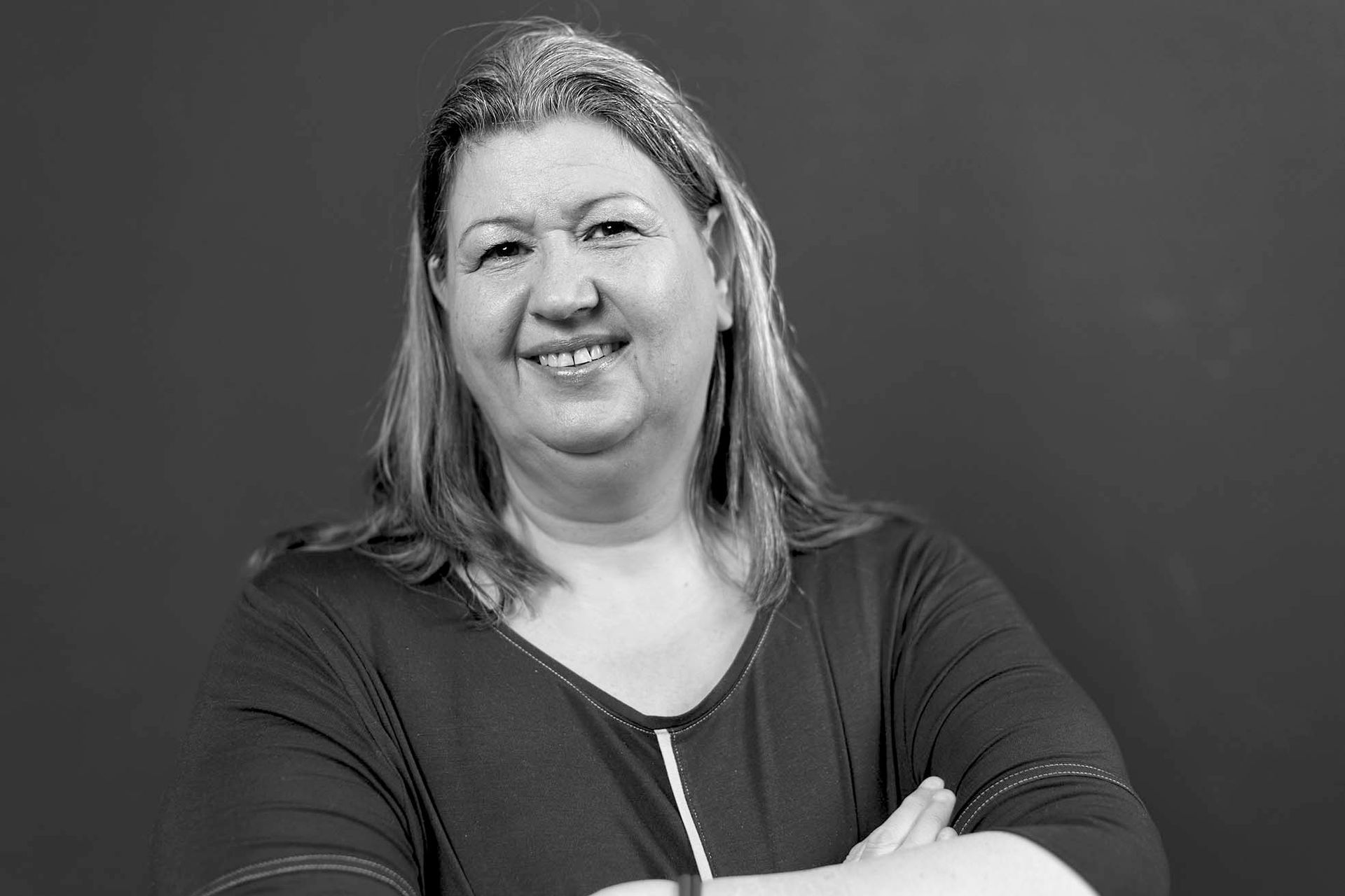 Auf einem Schwarzweißfoto lächelt eine Frau in einem schwarzen T-shirt.