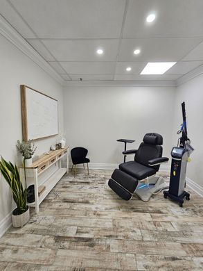 Modern white home office with black chair, desk, shelves, and patterned rug near shuttered windows.