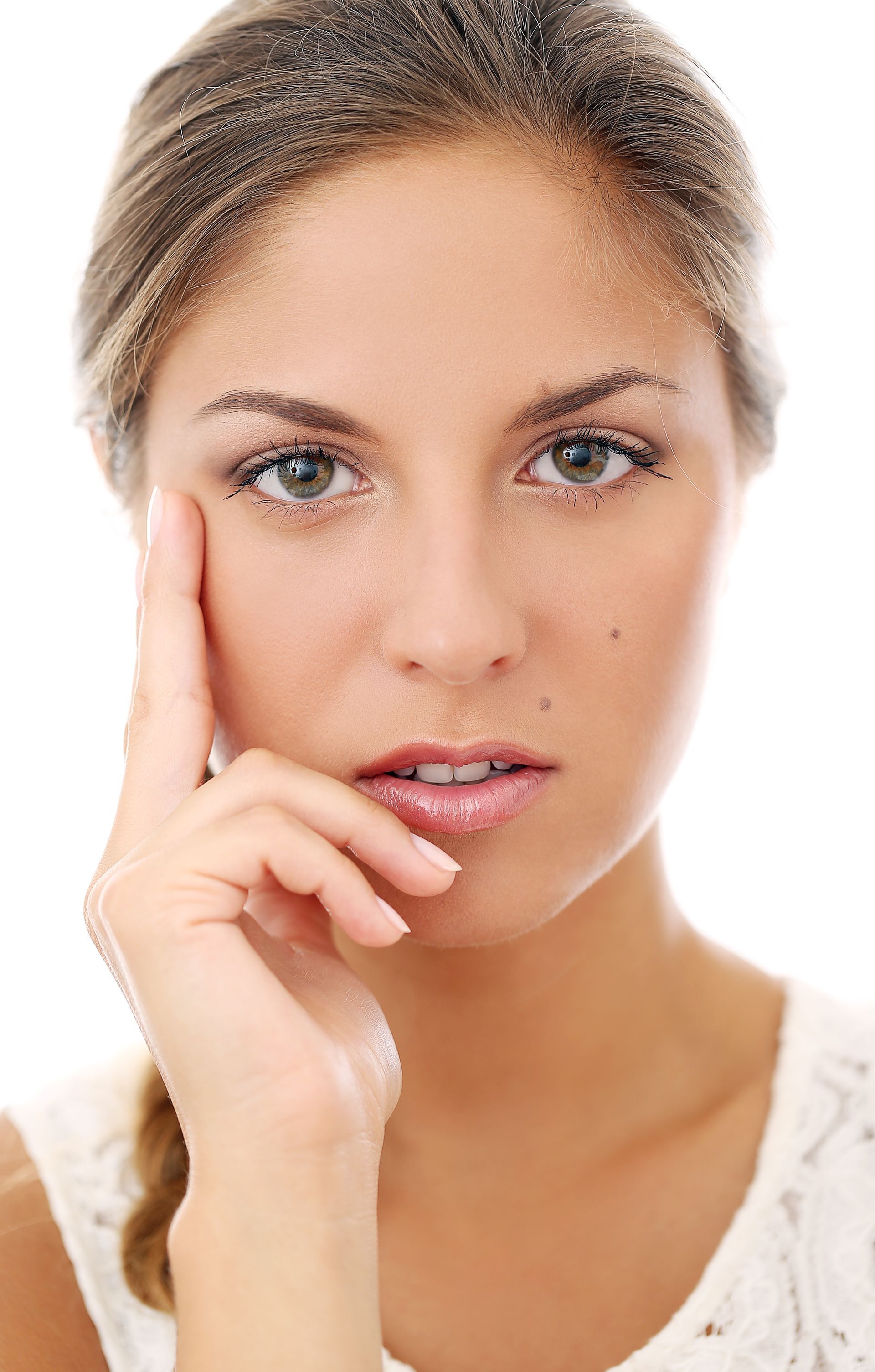 A woman is touching her face with her hand and looking at the camera.