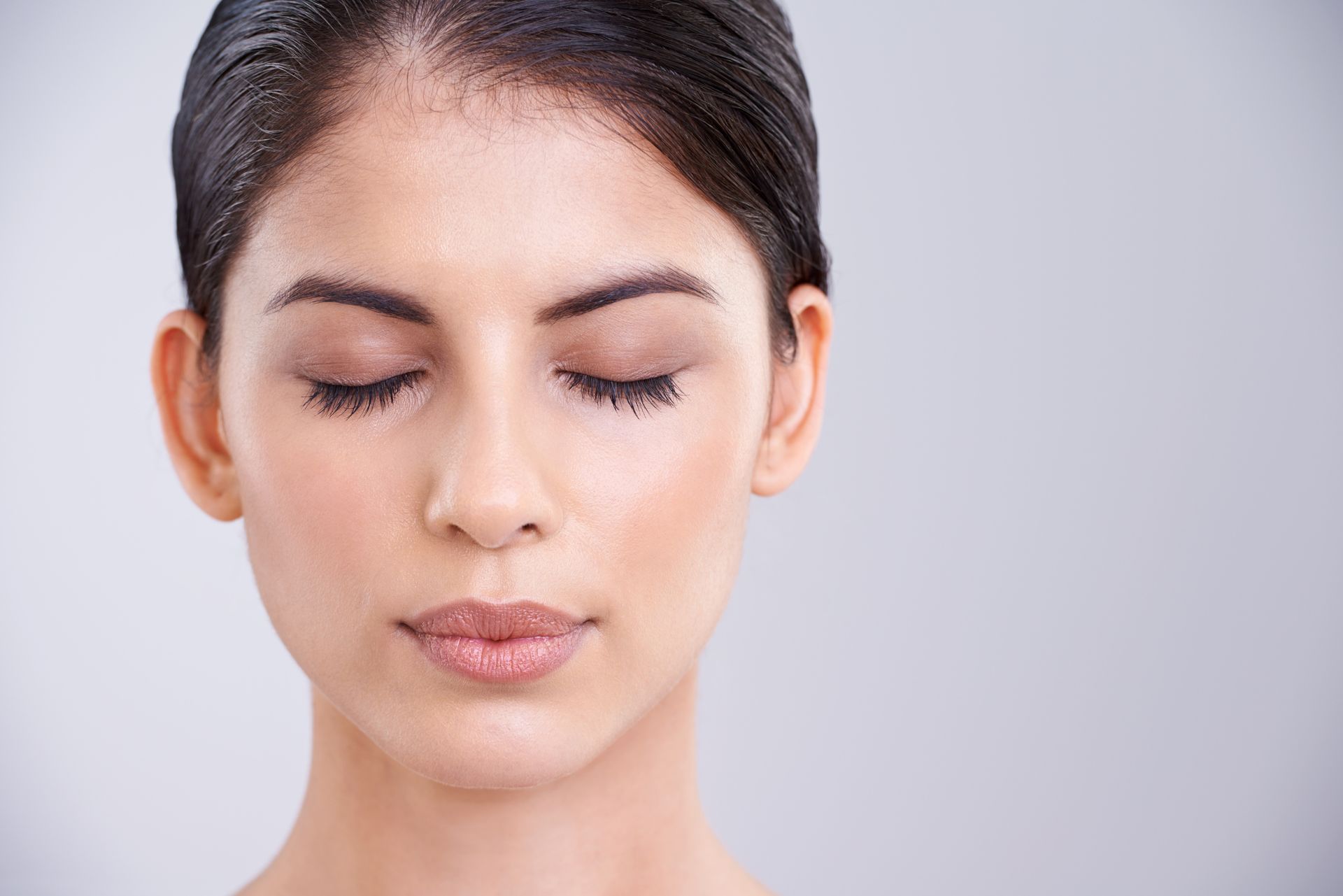 Close-up of a person with eyes closed against a light gray background