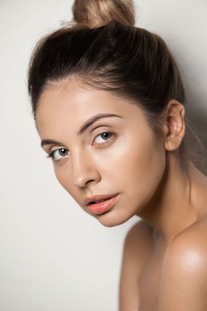 A woman with her hair in a bun is looking at the camera.