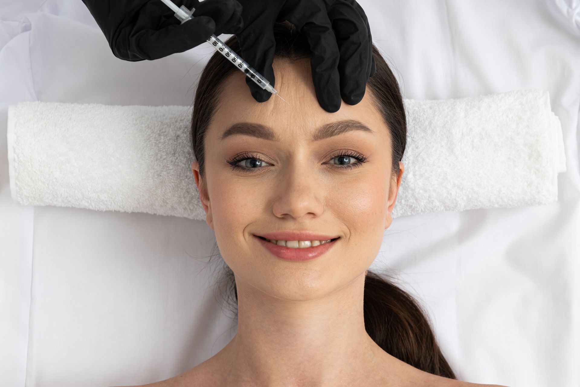 A woman is getting a botox injection in her forehead.