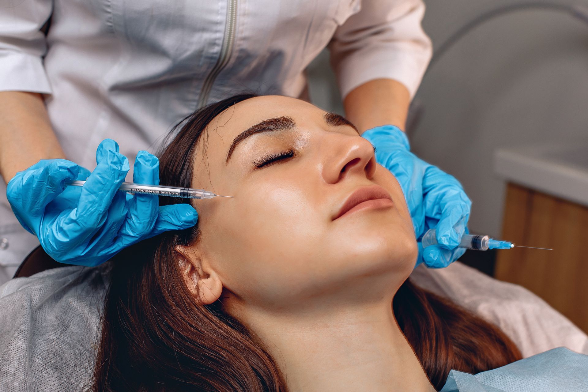 A woman is getting a botox injection in her face.