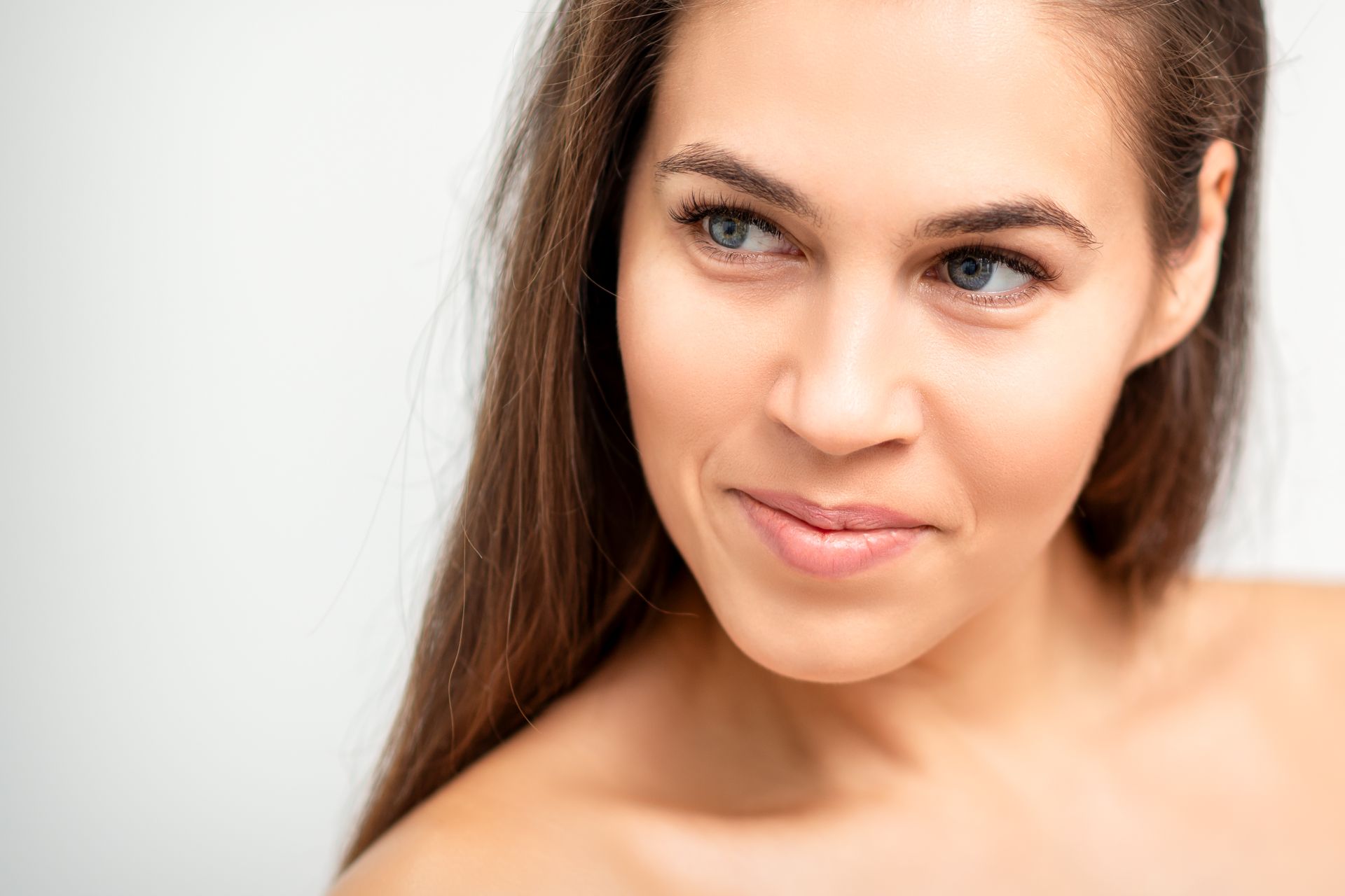 A close up of a woman 's face with long hair on a white background.