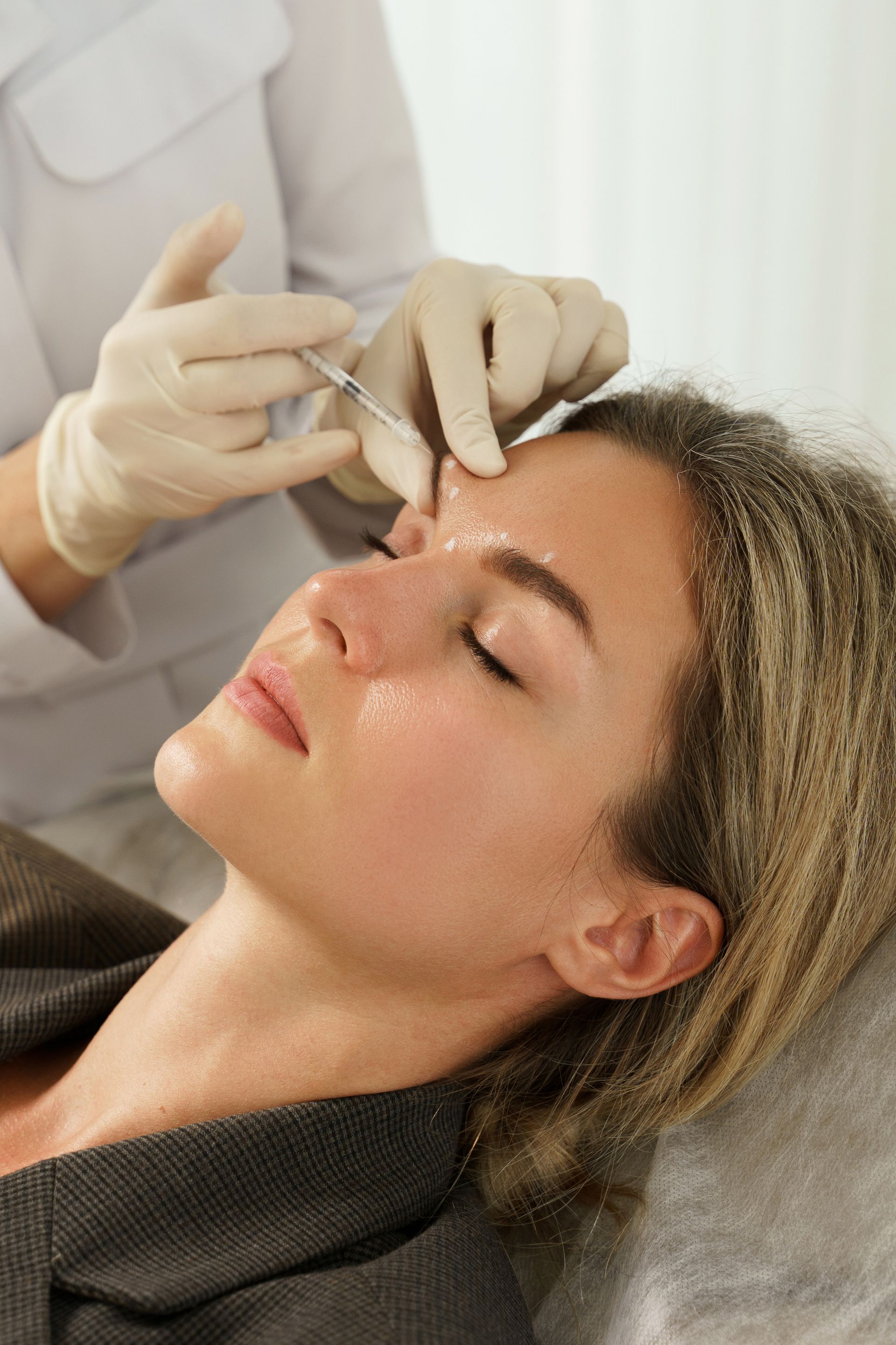 a woman is getting a botox injection in her forehead .