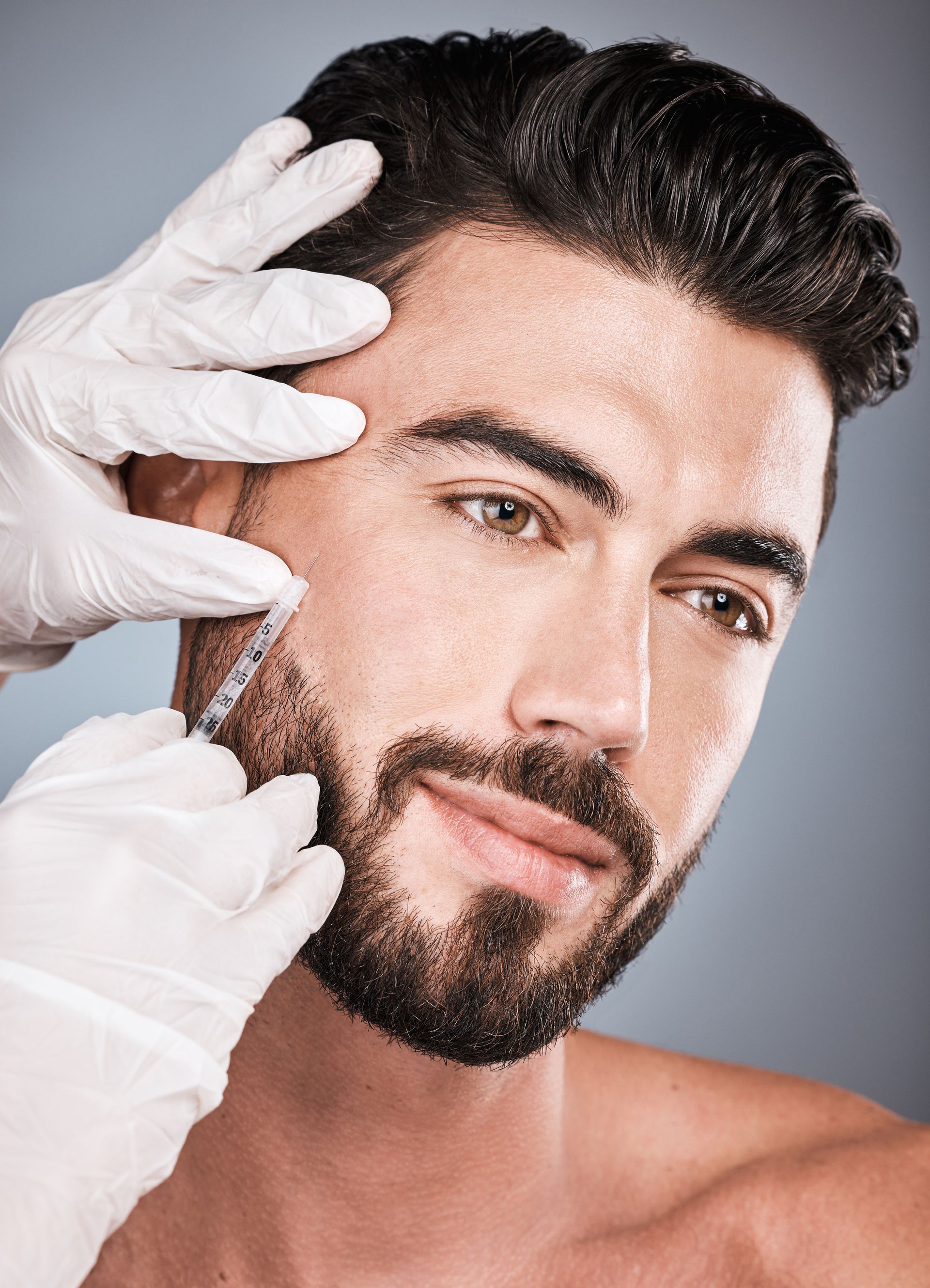 A man with a beard is getting a botox injection in his forehead.