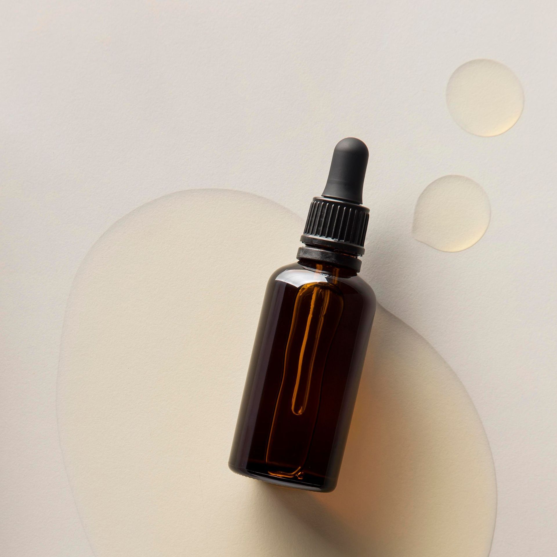 a brown bottle with a dropper on top of a white surface .