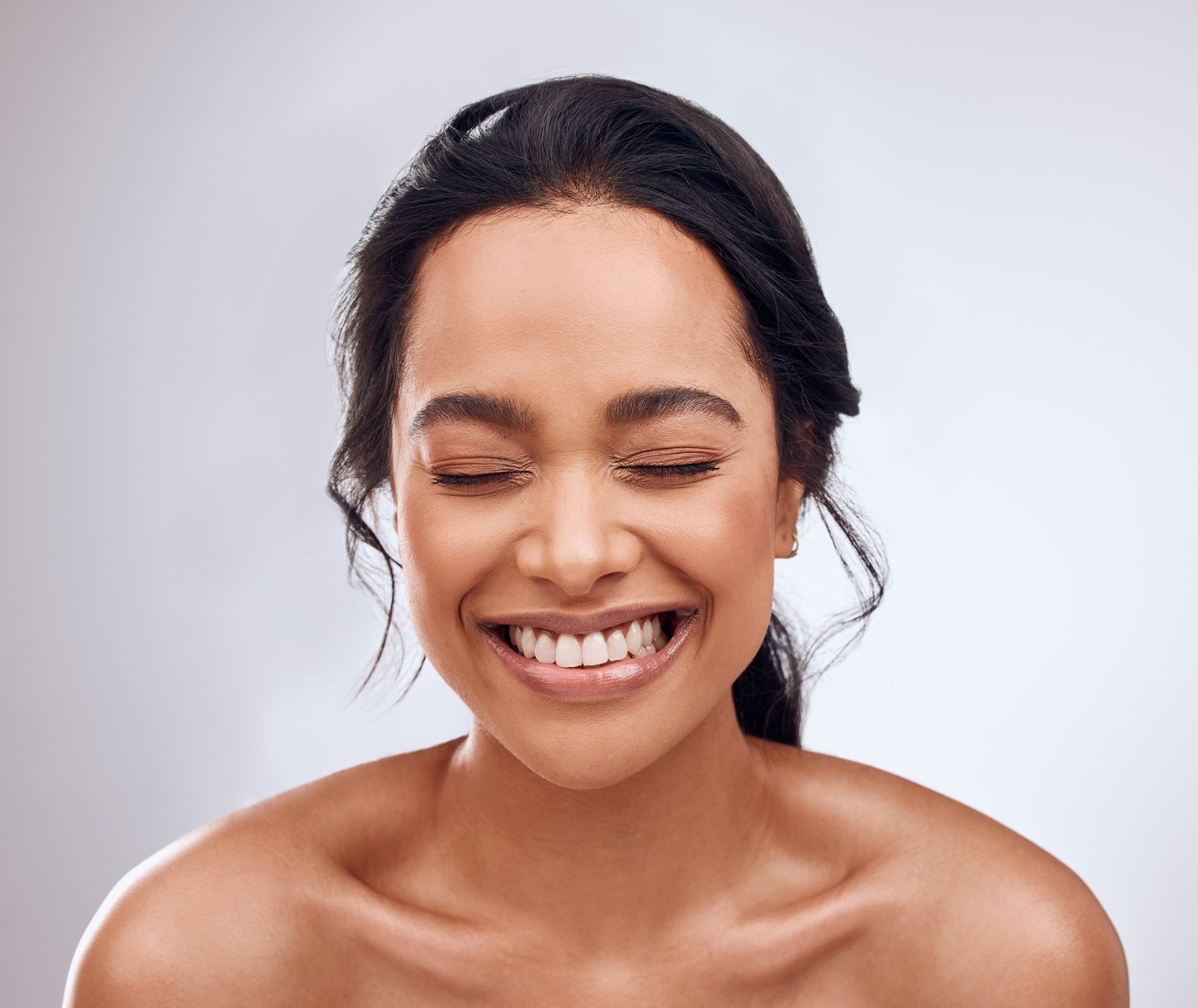 A woman is smiling with her eyes closed and her mouth open.
