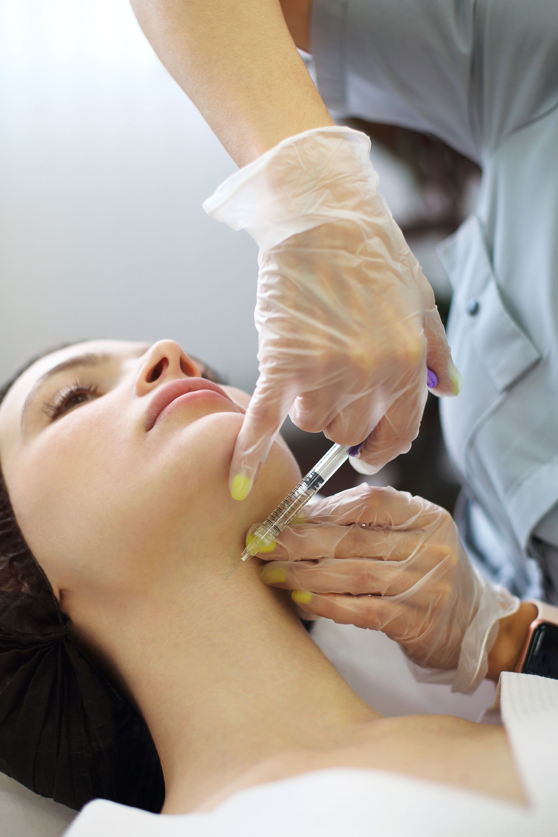 A woman is getting a botox injection in her neck.