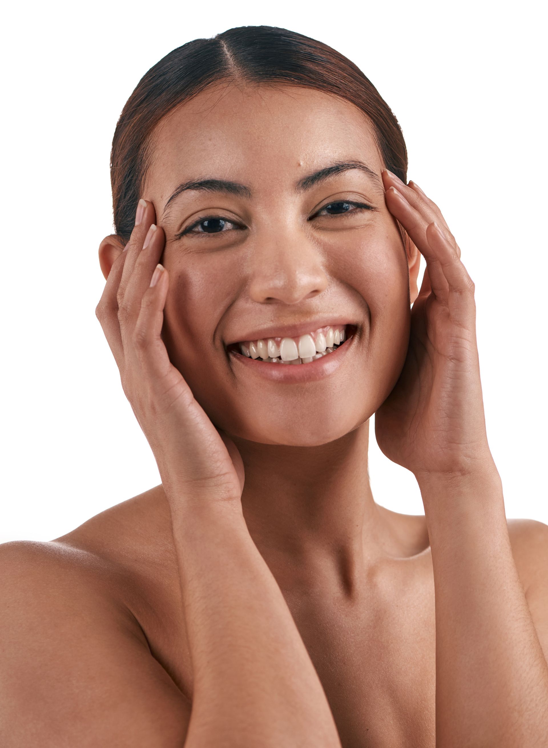 A woman is smiling and touching her face with her hands.