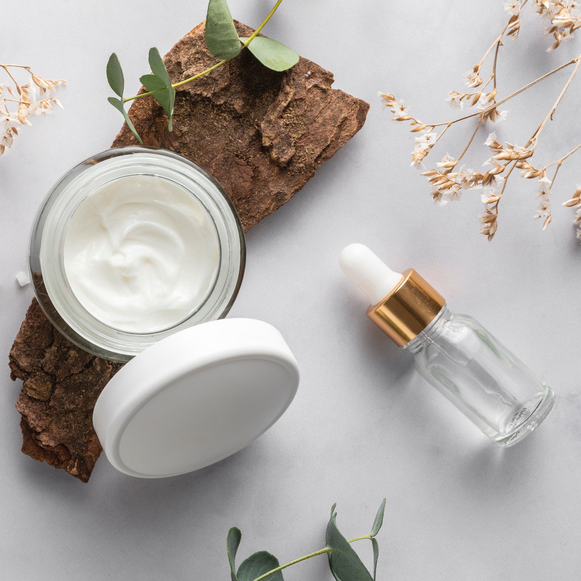 a jar of cream and a bottle of serum are on a table .