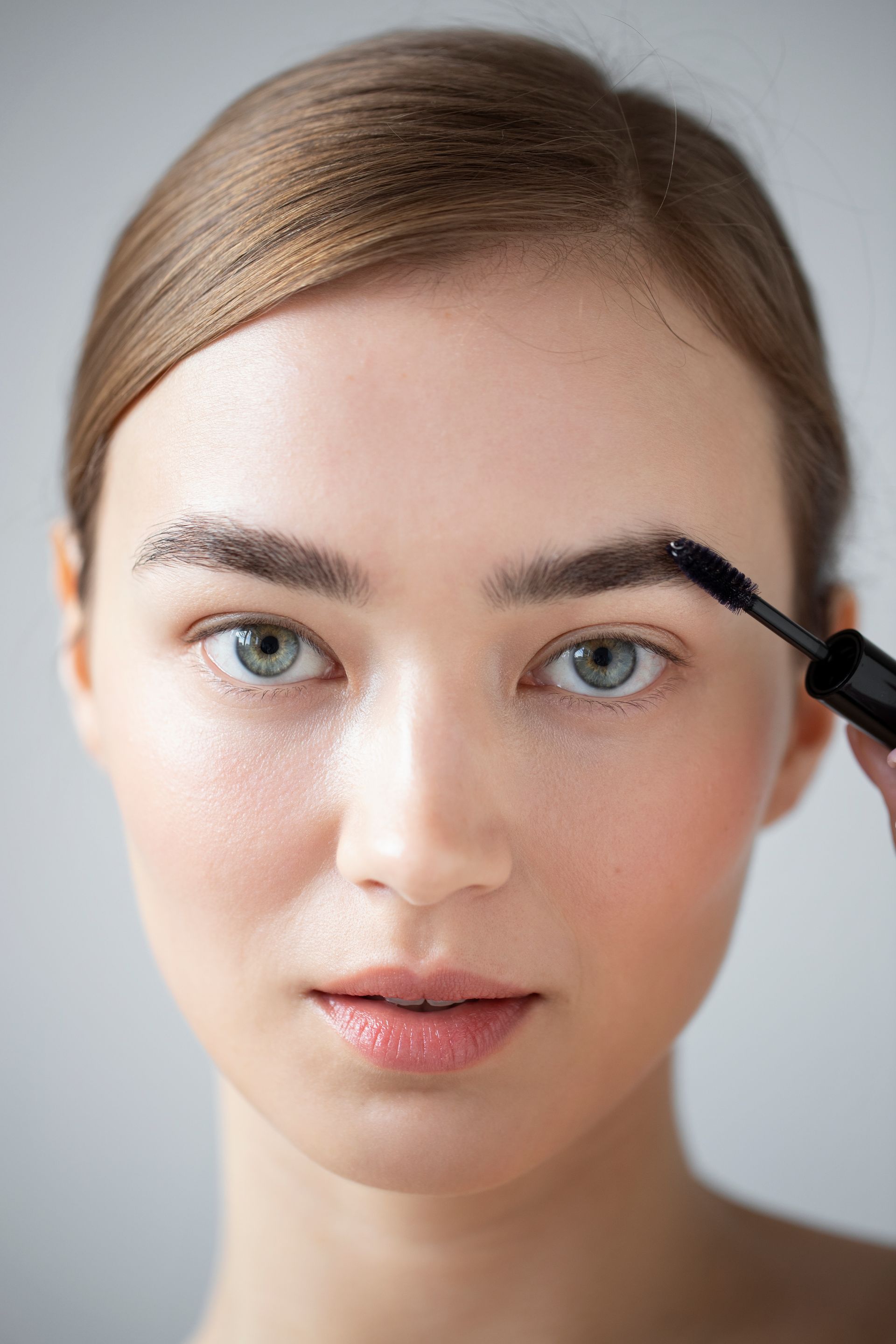 a woman is applying mascara to her eyebrows .