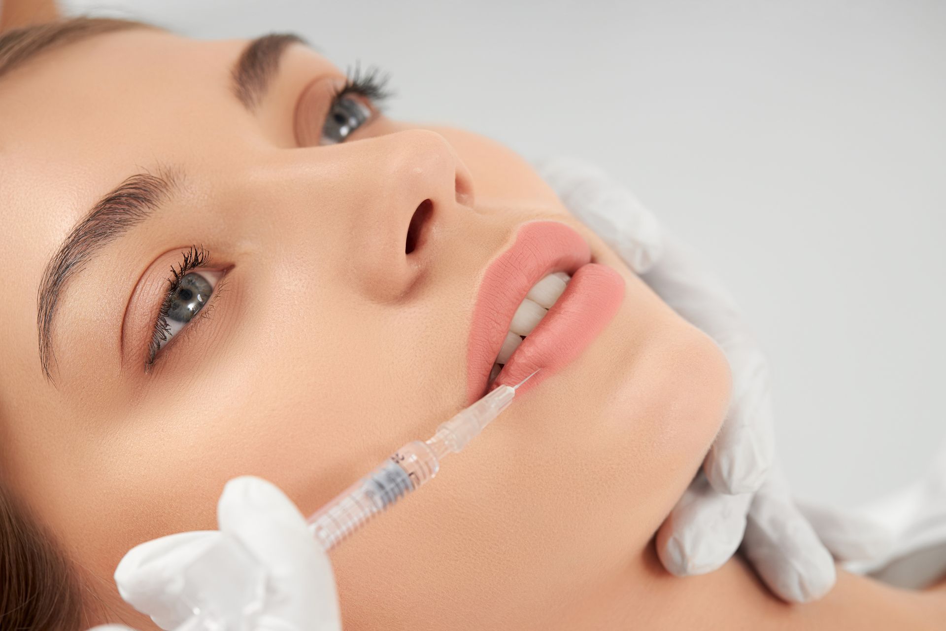 A woman is getting a botox injection in her lips.