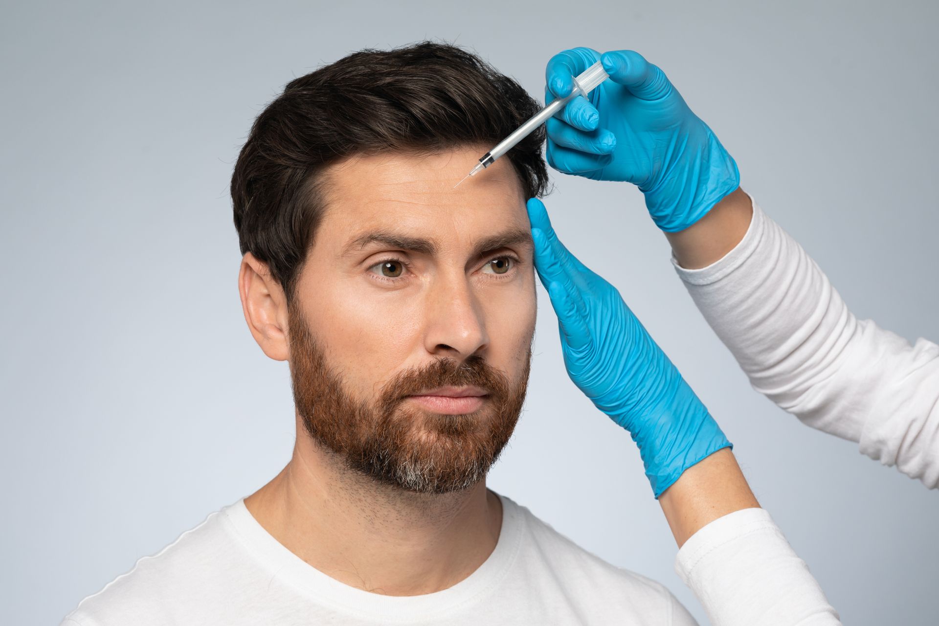 A man is getting a botox injection in his forehead.