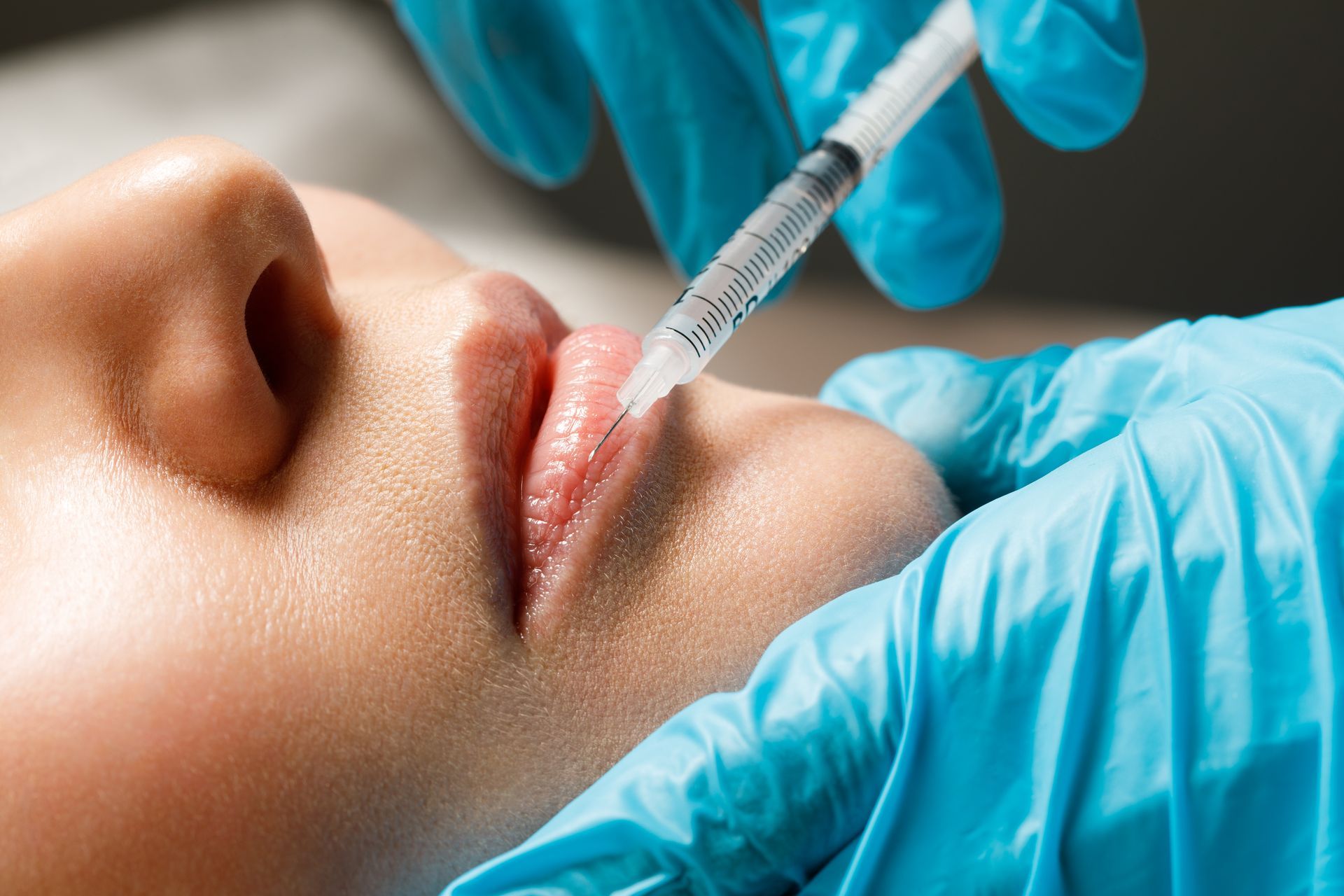 A woman is getting a botox injection in her lips.