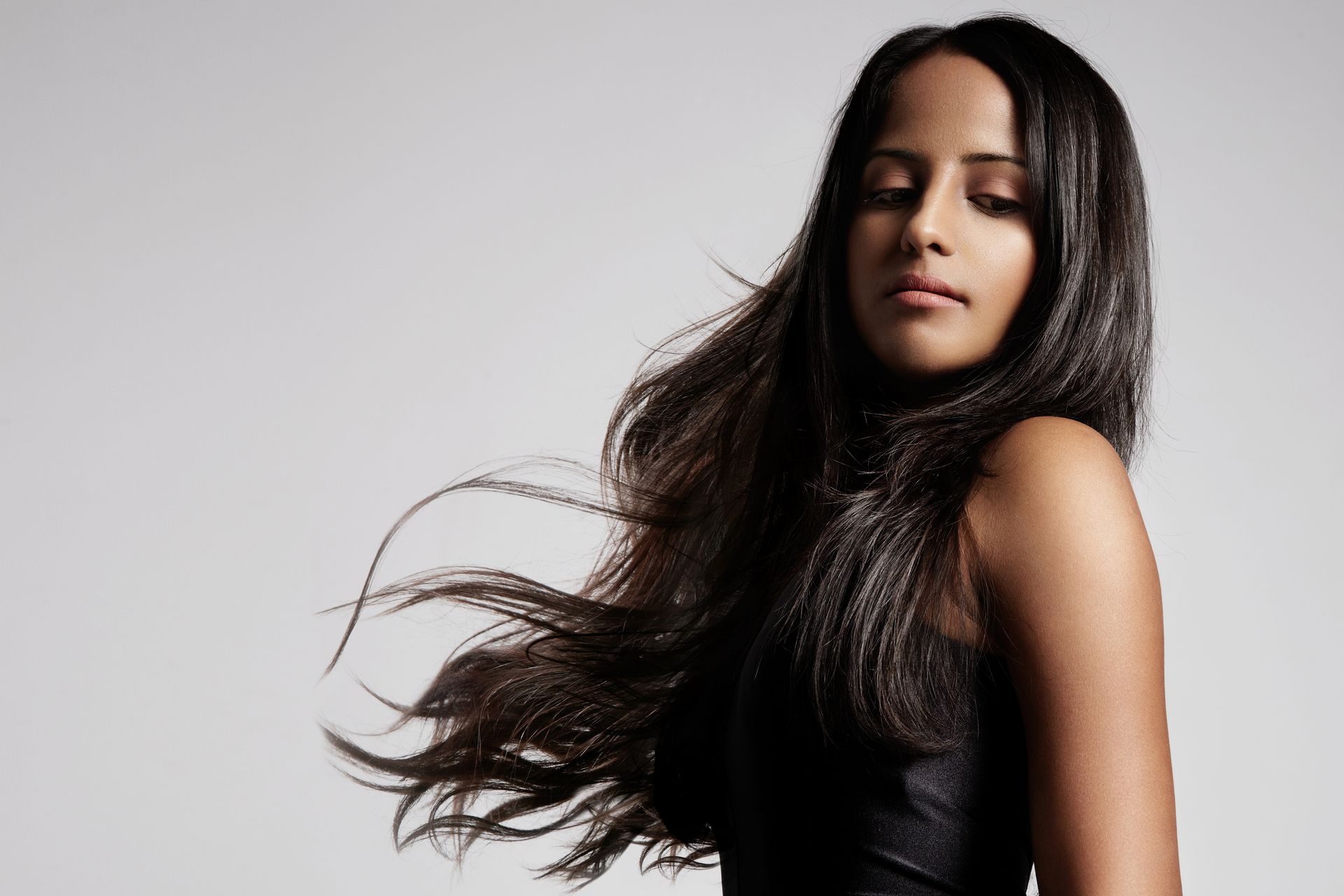 A woman with long dark hair is wearing a black dress