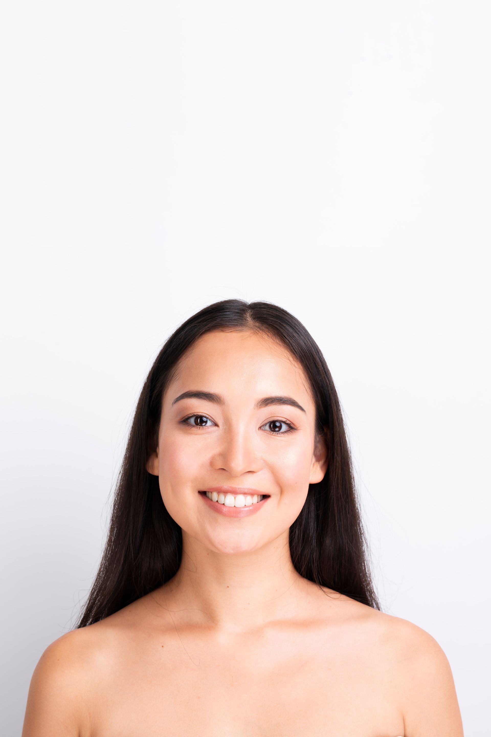 A woman without a shirt is smiling and looking at the camera.