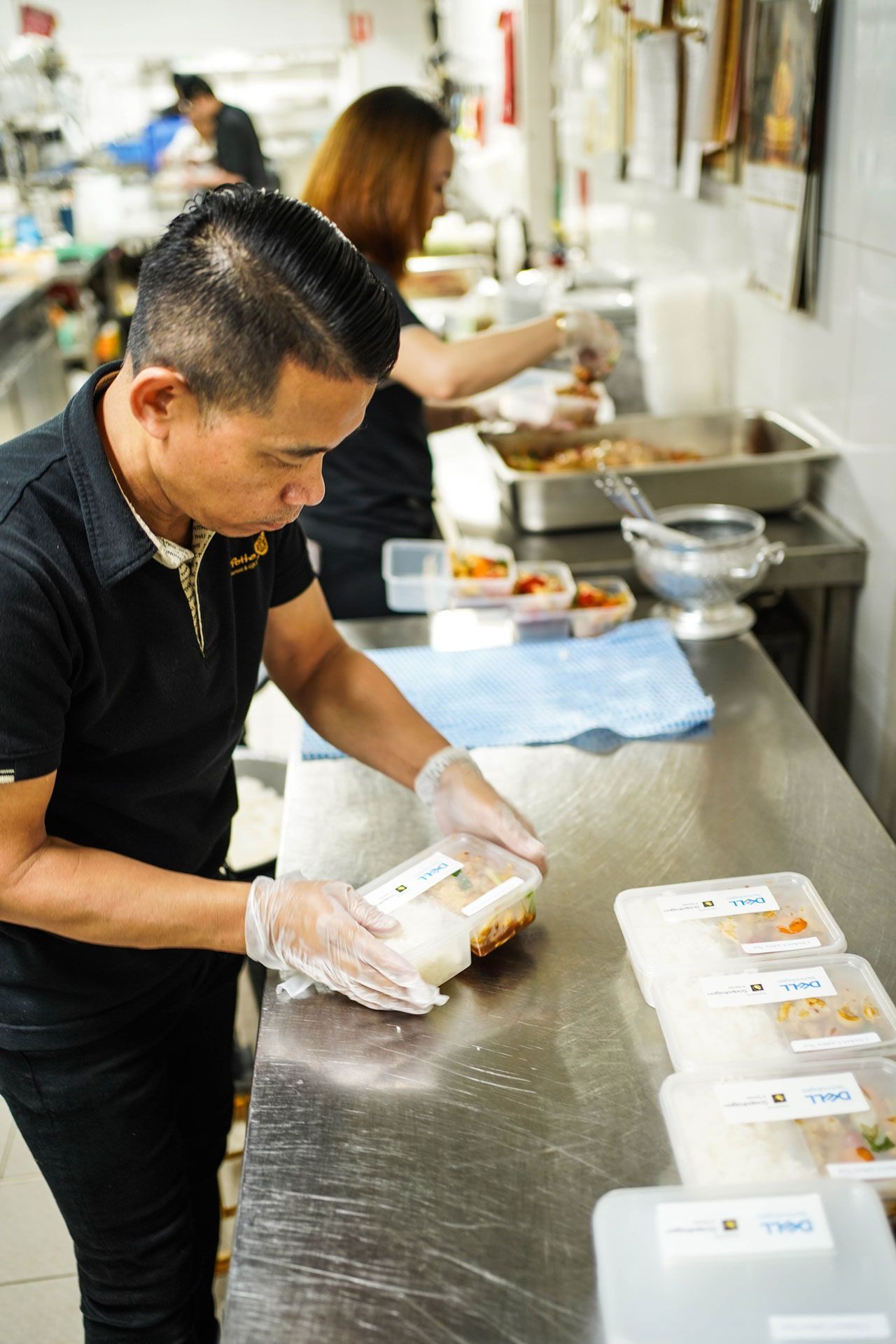 A man and a woman are preparing Thai food in a kitchen.