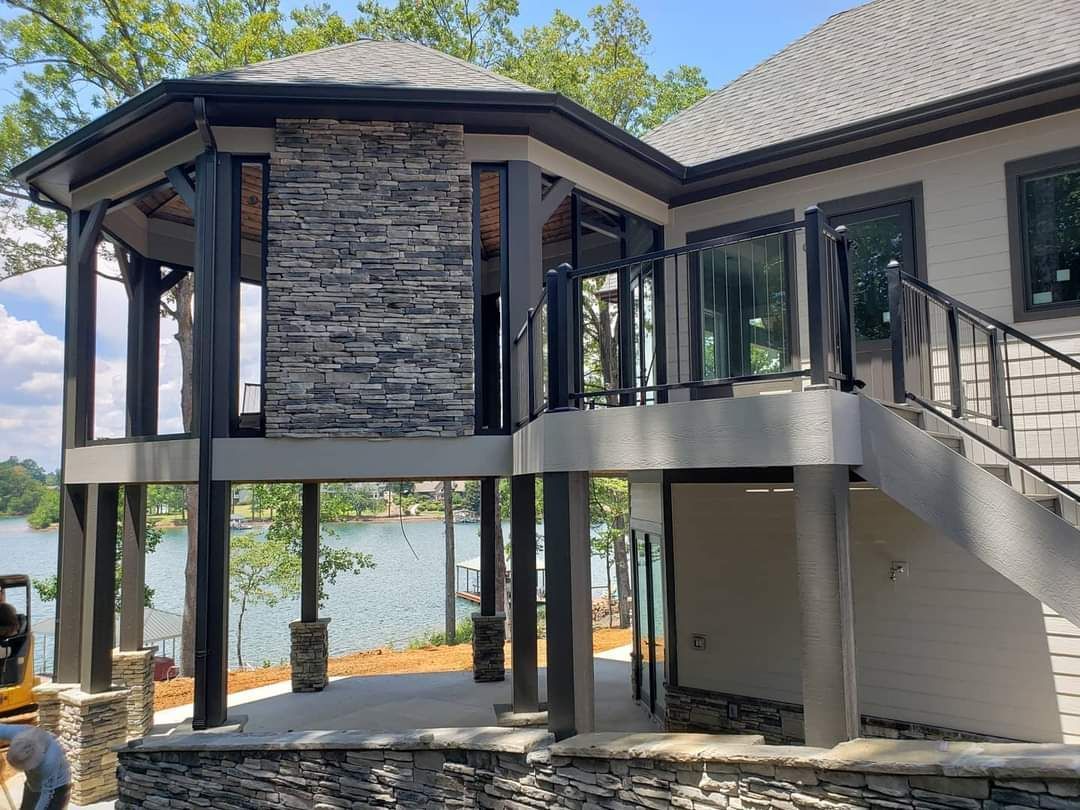 a house with stairs leading up to a balcony overlooking a lake