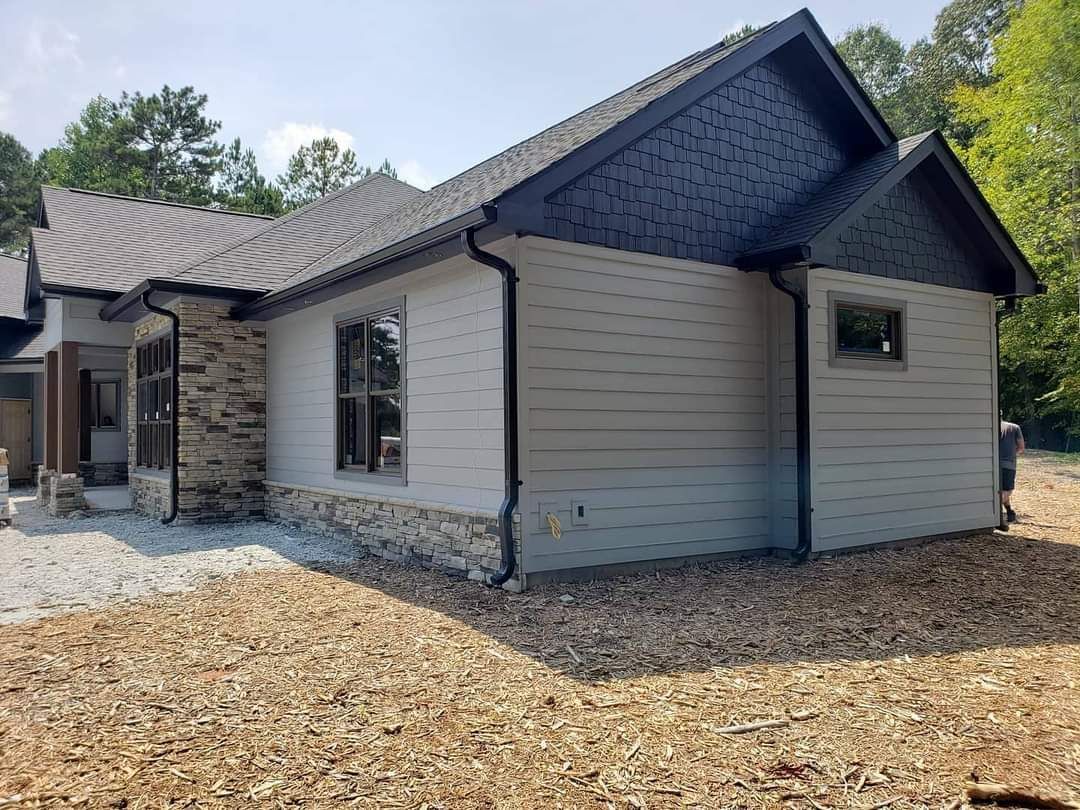 a house with a lot of windows is sitting on top of a dirt field