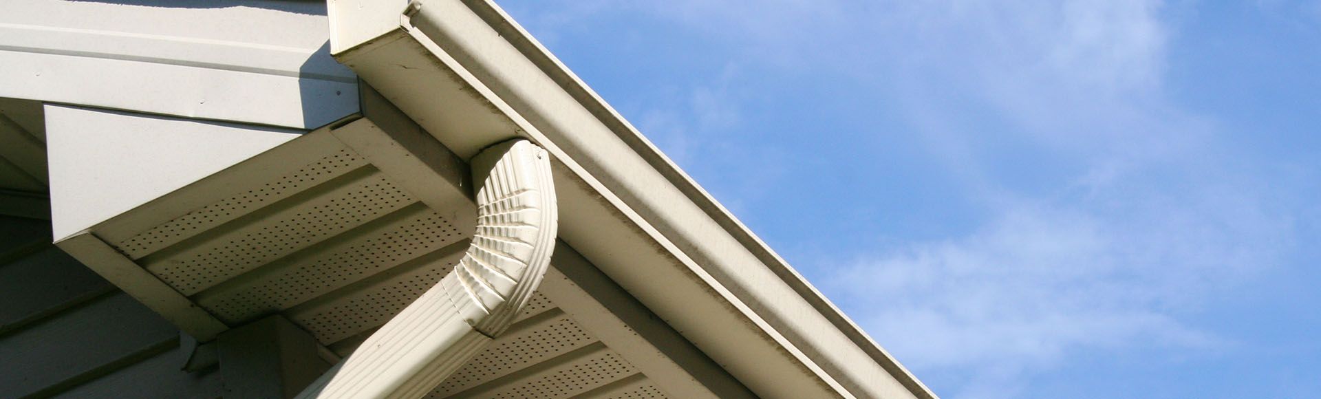 a gutter on the side of a house with a blue sky in the background