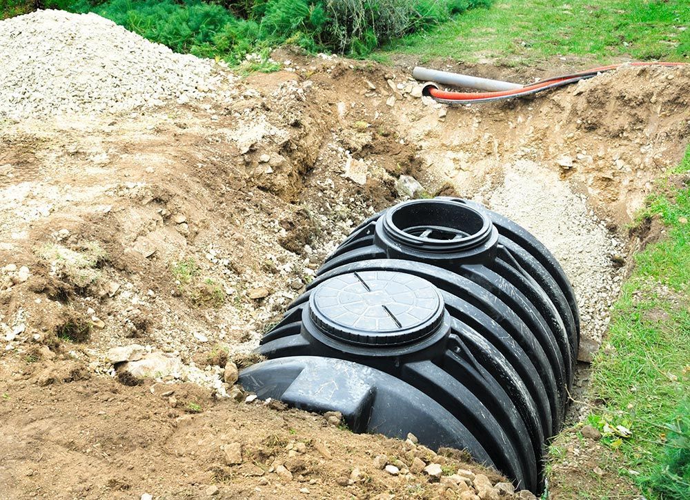 A large black septic tank is being built in the dirt.