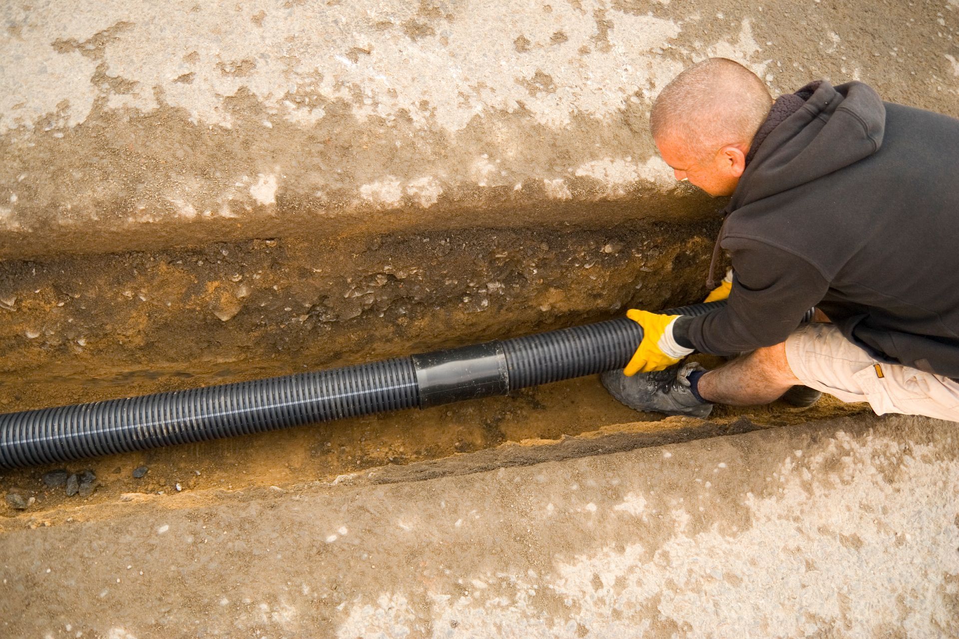 A man is laying a pipe in the dirt.