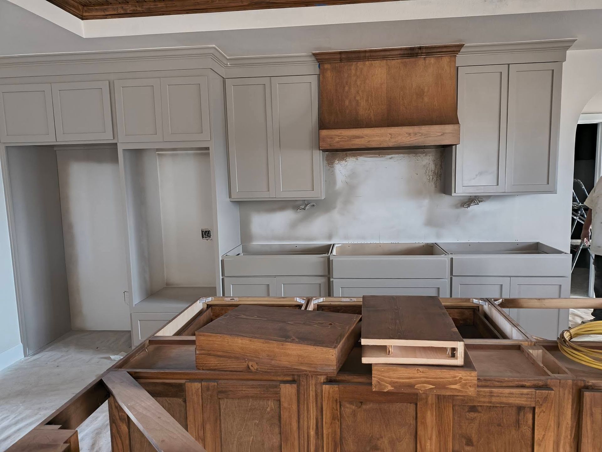 Kitchen under renovation with unfinished white cabinets and a wood island in the foreground