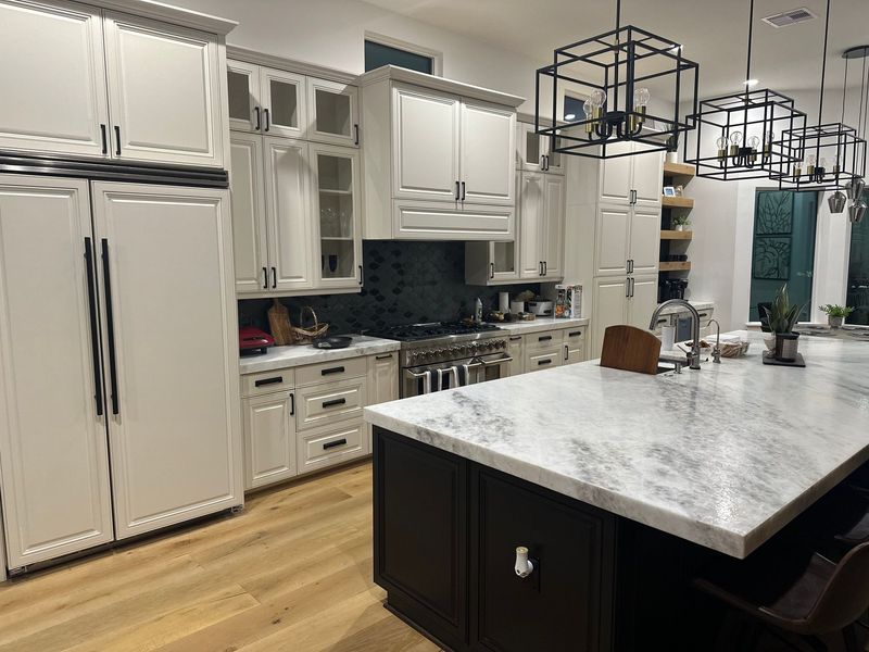 Modern kitchen with white cabinets, large island, stainless appliances, and wood flooring